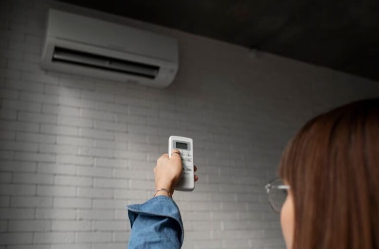Una mujer ajustando la temperatura del aire acondicionado